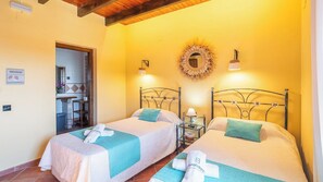 A hotel room with two beds, a small table with a lamp, a mirror on the wall, and a door leading to a bathroom. - La Casita del Campo Alcaucín by Ruralidays (Málaga)