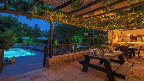Un patio al aire libre con piscina, zona de comedor y cocina.
