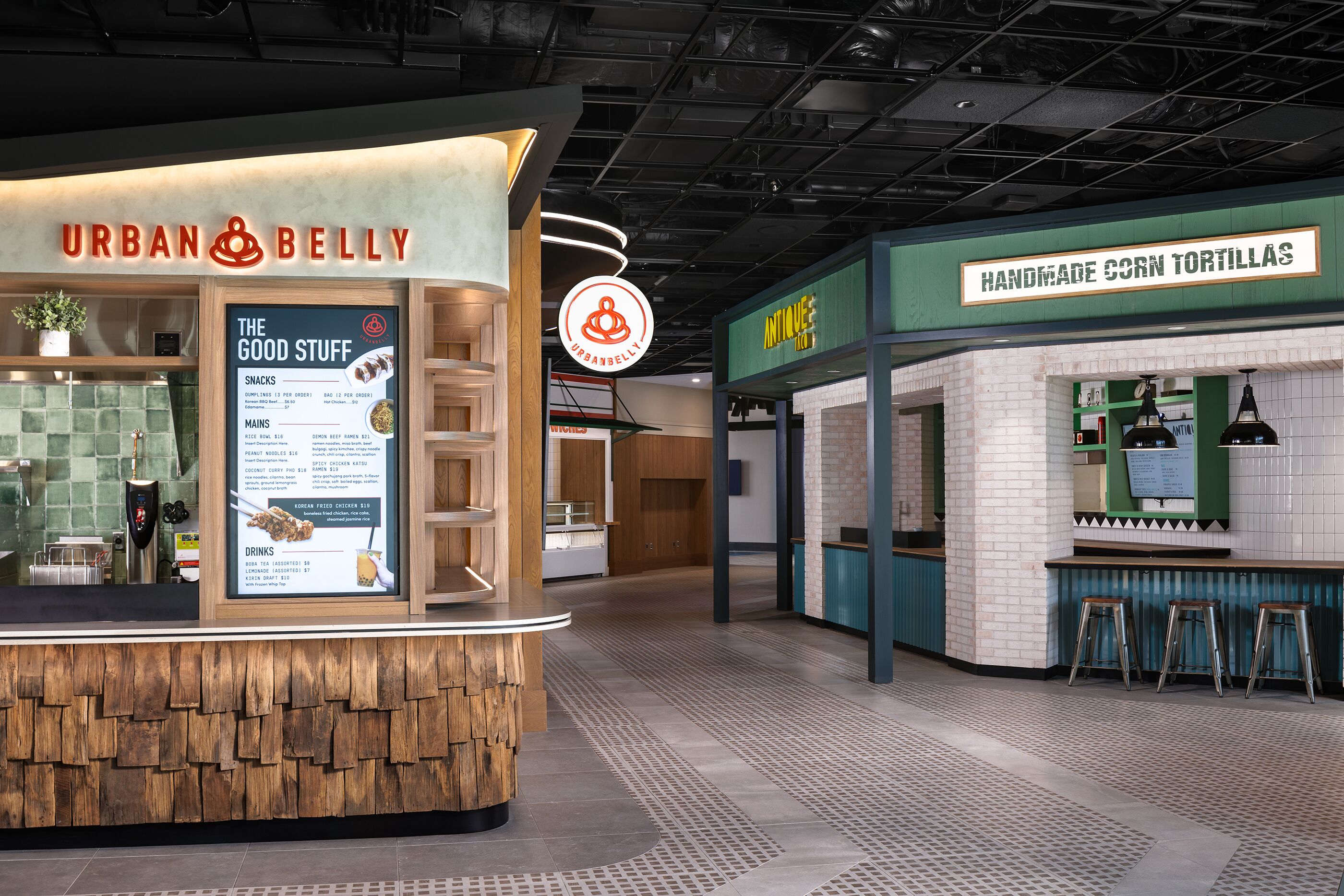 A food court with a sign for 'Urban Belly' and another for 'Handmade Corn Tortillas.'