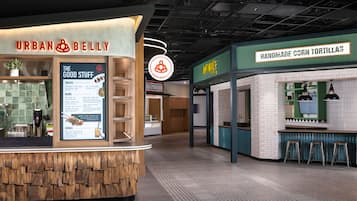 A food court with a sign for 'Urban Belly' and another for 'Handmade Corn Tortillas.'