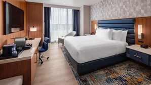 Ein Hotelzimmer mit Bett, Schreibtisch, Stuhl und einem großen Fenster.