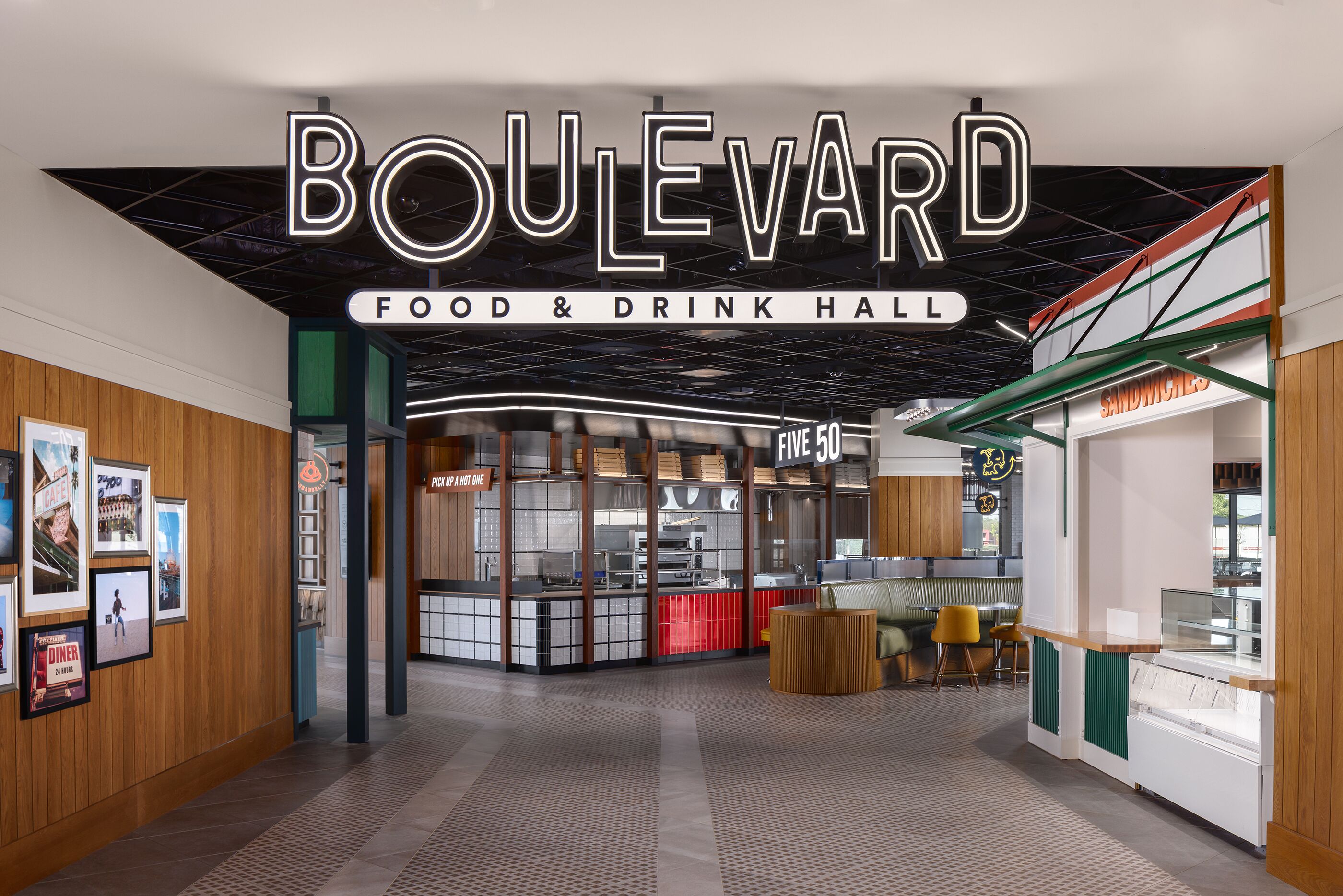 A food and drink hall with a sign reading 'Boulevard Food & Drink Hall,' a counter with a glass display, and a seating area with chairs.