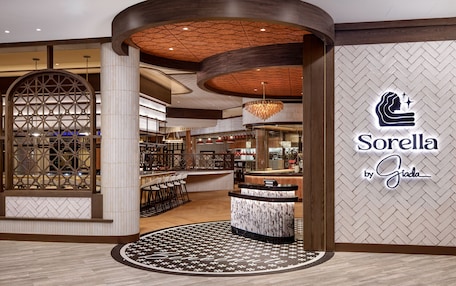 A modern interior with a reception desk, a herringbone patterned wall, and a chandelier.
