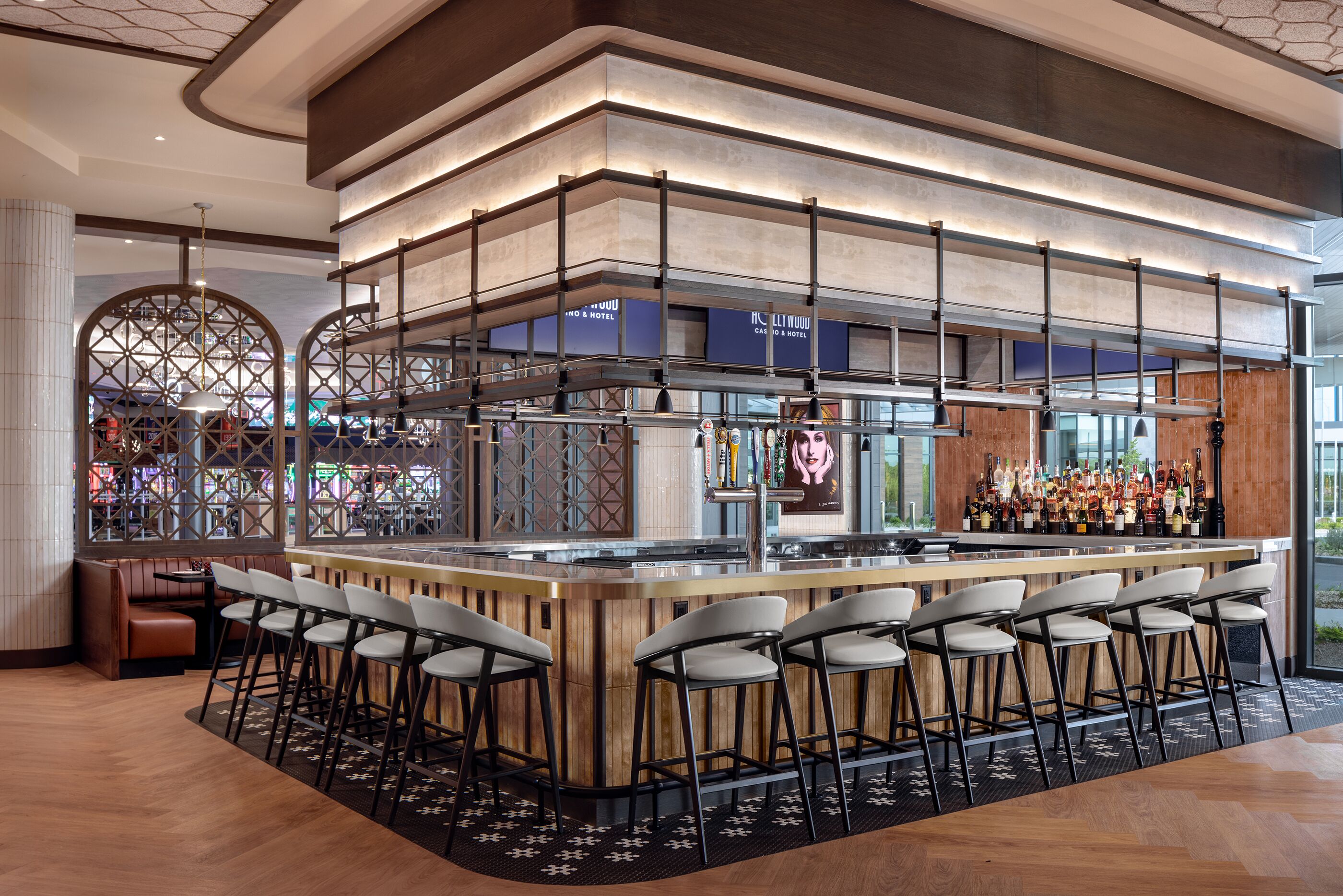 A bar area with a high counter, multiple stools, and a variety of bottles.
