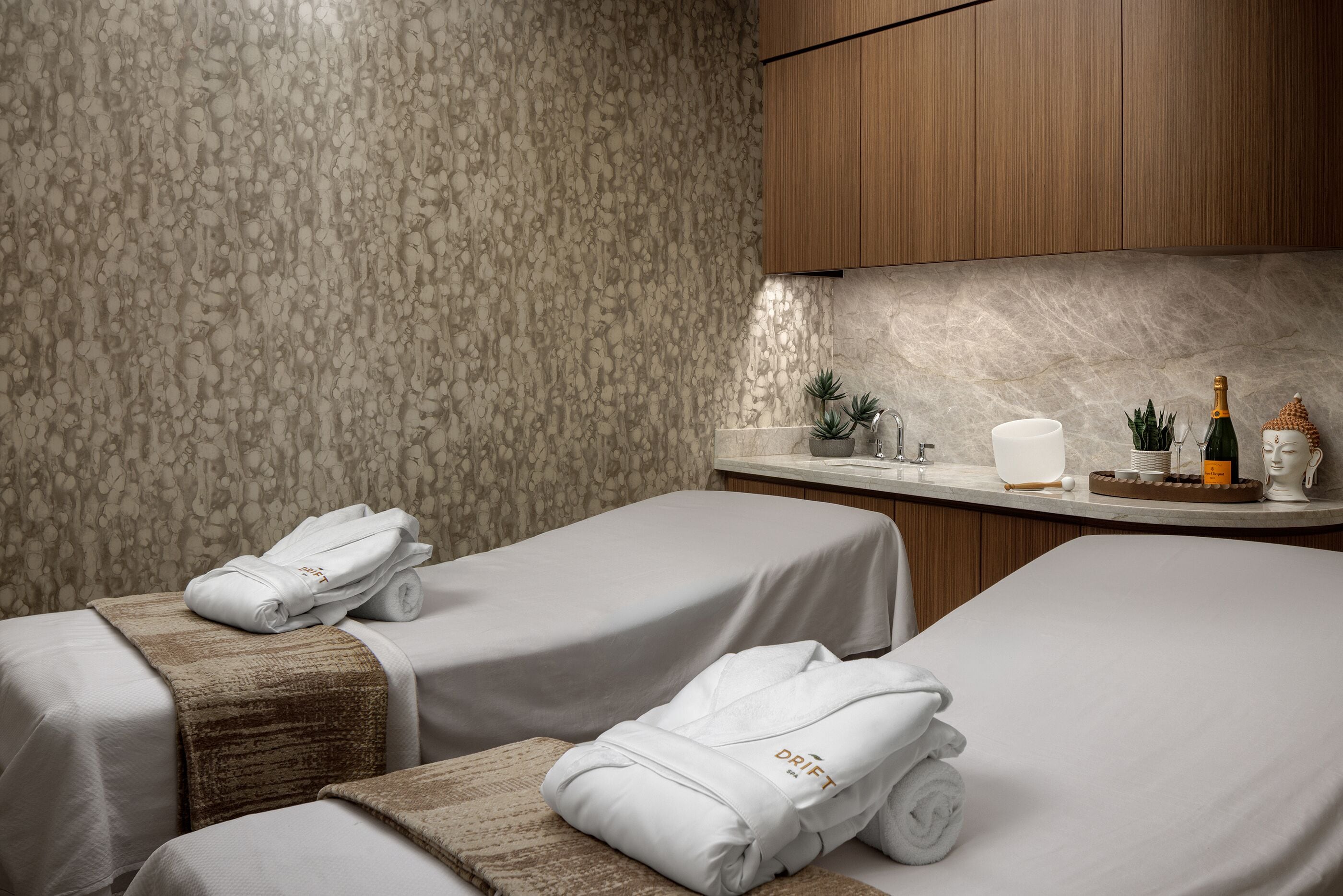 A hotel room with two beds, a minibar, and a bathroom.