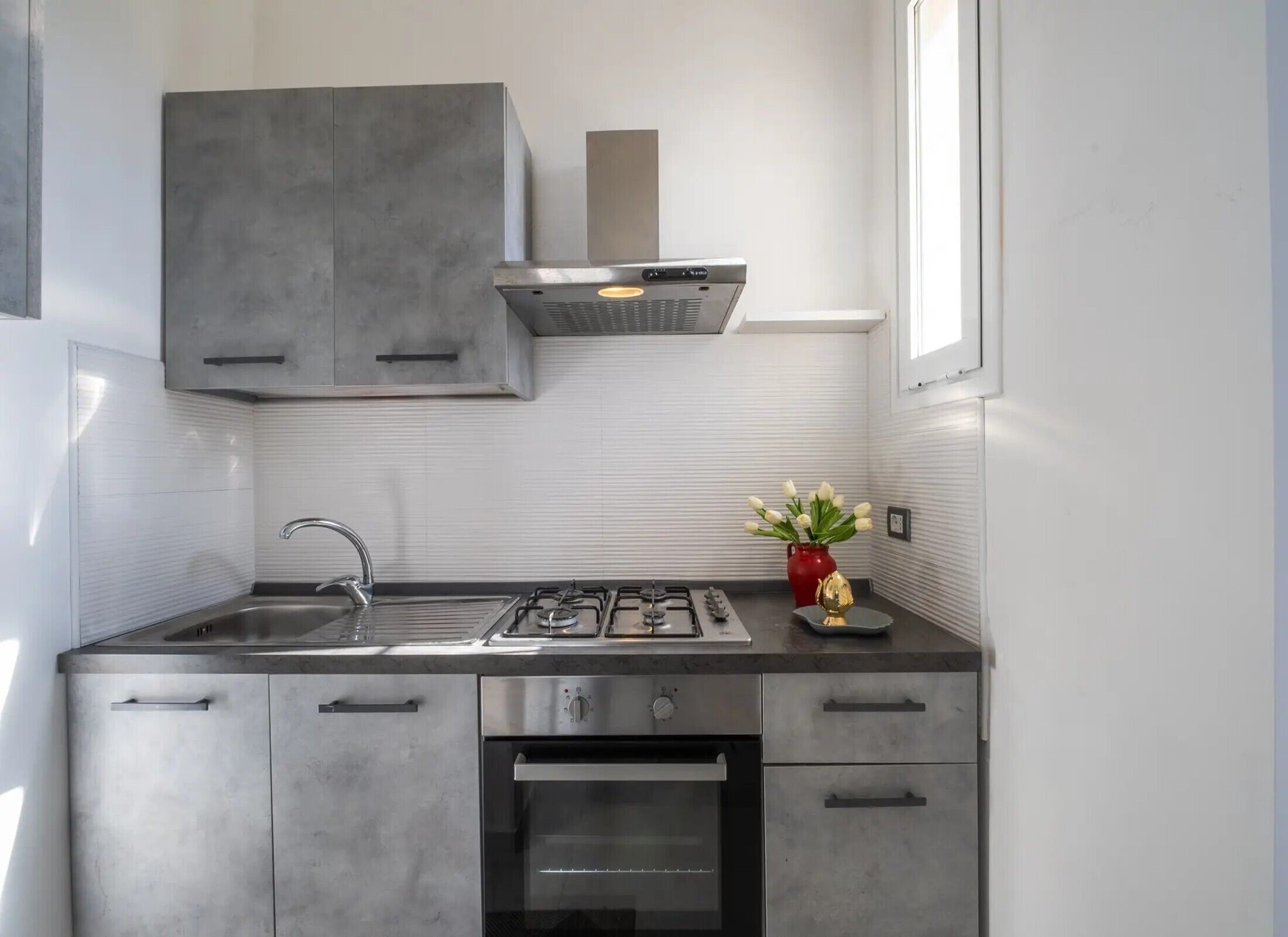 Et moderne køkken med gaskogeplade, ovn, skabe i rustfrit stål og et vindue.