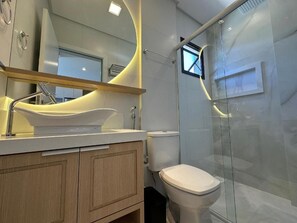 A modern bathroom with a white sink, a toilet, and a glass-enclosed shower. - Mirante do Oceano guesthouse, 70 meters from the beach, with a heated pool. (Bombinhas)