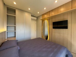 A bedroom with a bed, built-in wardrobe, and a wall-mounted TV. - Mirante do Oceano guesthouse, 70 meters from the beach, with a heated pool. (Bombinhas)