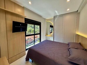 A bedroom with a bed, a television, and a window with a view. - Mirante do Oceano guesthouse, 70 meters from the beach, with a heated pool. (Bombinhas)