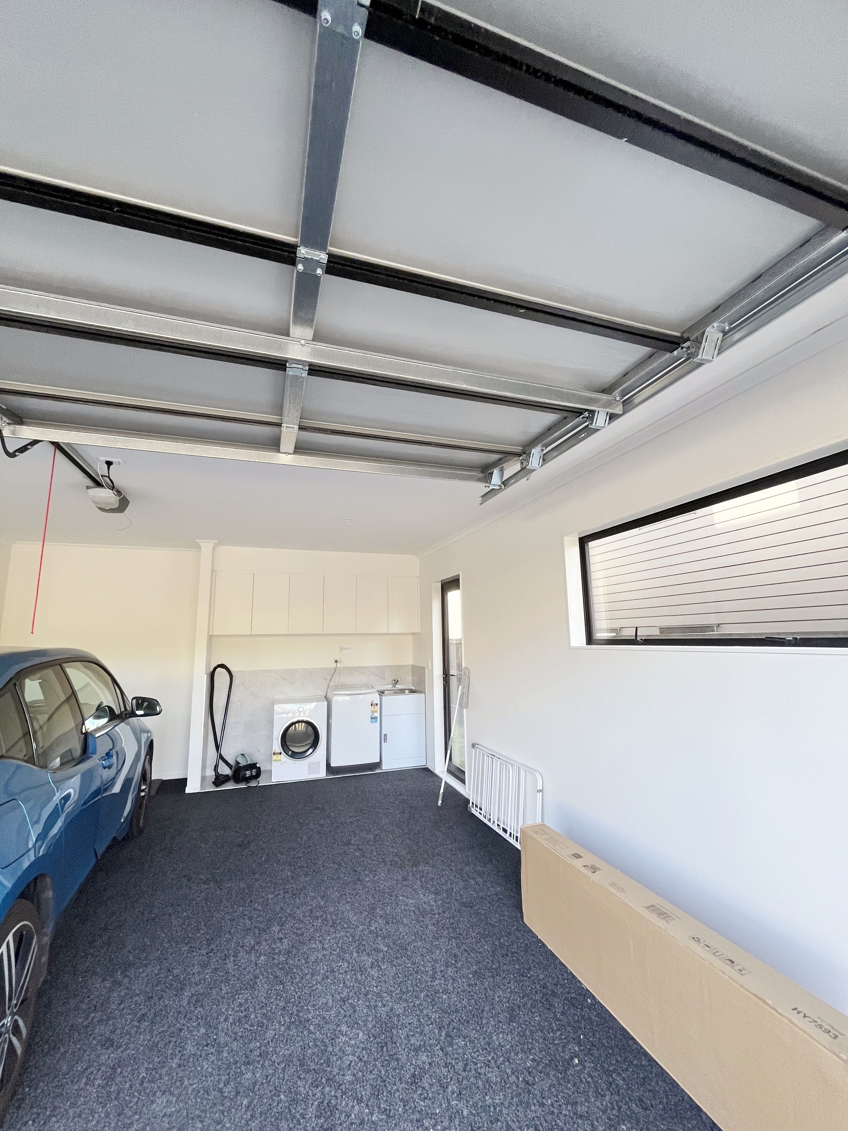 A garage with a car, a washing machine, and a dryer.