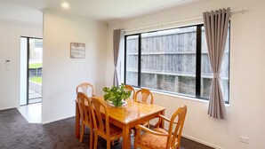 A dining room with a wooden table and chairs, a potted plant, and a window with curtains. - Riverview Sunset Getaway - 4 bedroom 2.5 bathroom and stunning view (Hamilton)