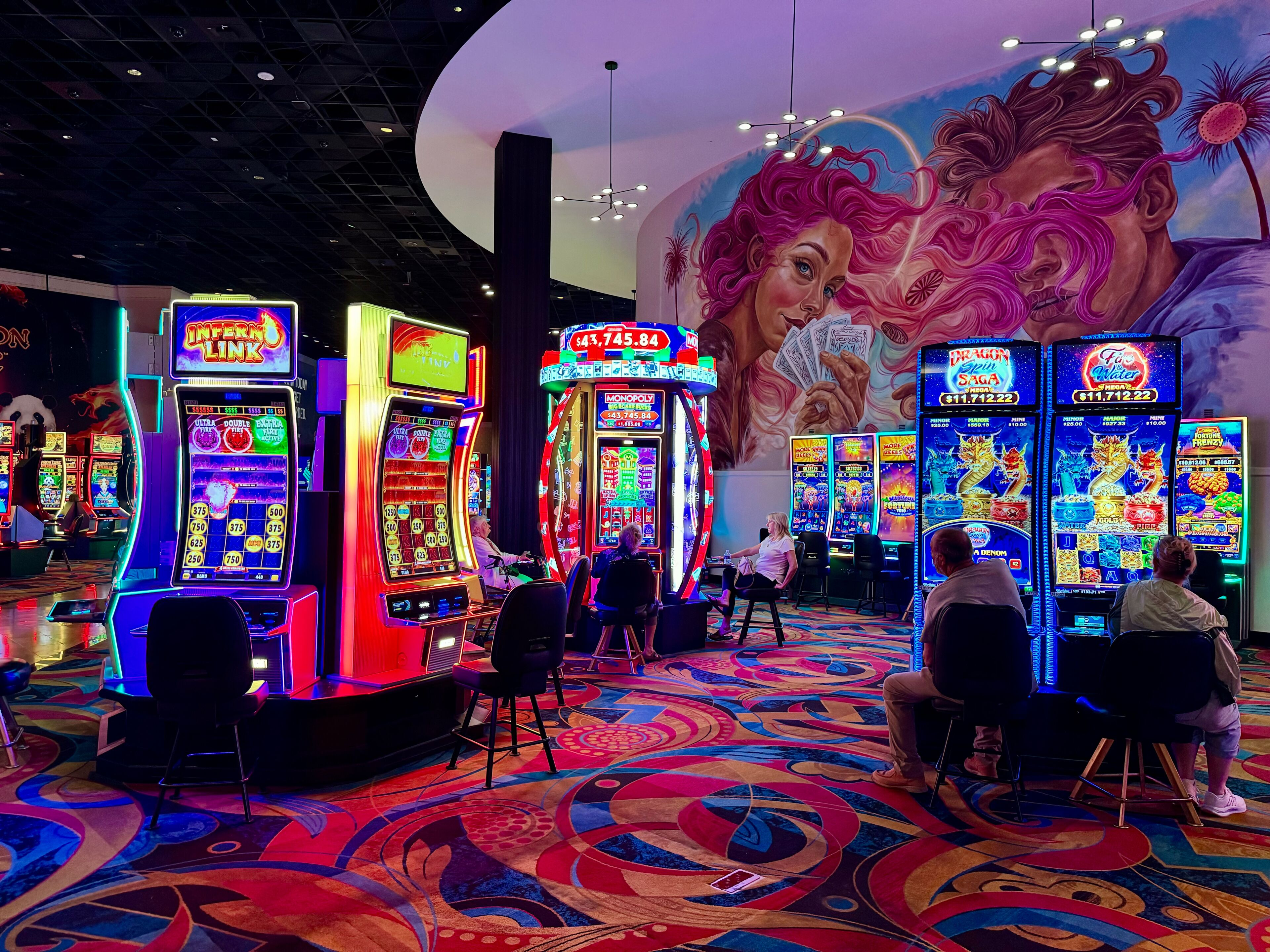 Un casino con máquinas tragamonedas y un mural en la pared.
