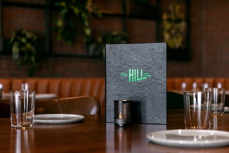 A restaurant setting with a menu board, empty plates, glasses, and a candle on the table.