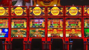 Een rij gokautomaten met verlichte schermen, elk met verschillende spelthema’s.