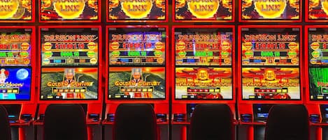 Una fila di slot machine con schermi illuminati, ognuno con temi di gioco diversi.