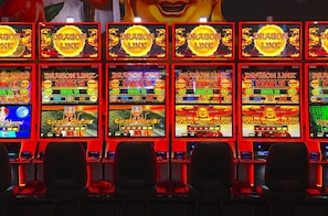 Una hilera de máquinas tragamonedas con pantallas iluminadas, cada una mostrando diferentes temas de juego.