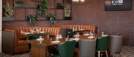 Un restaurante con pared de ladrillo, plantas verdes, una mesa de madera y un asiento de cabina.