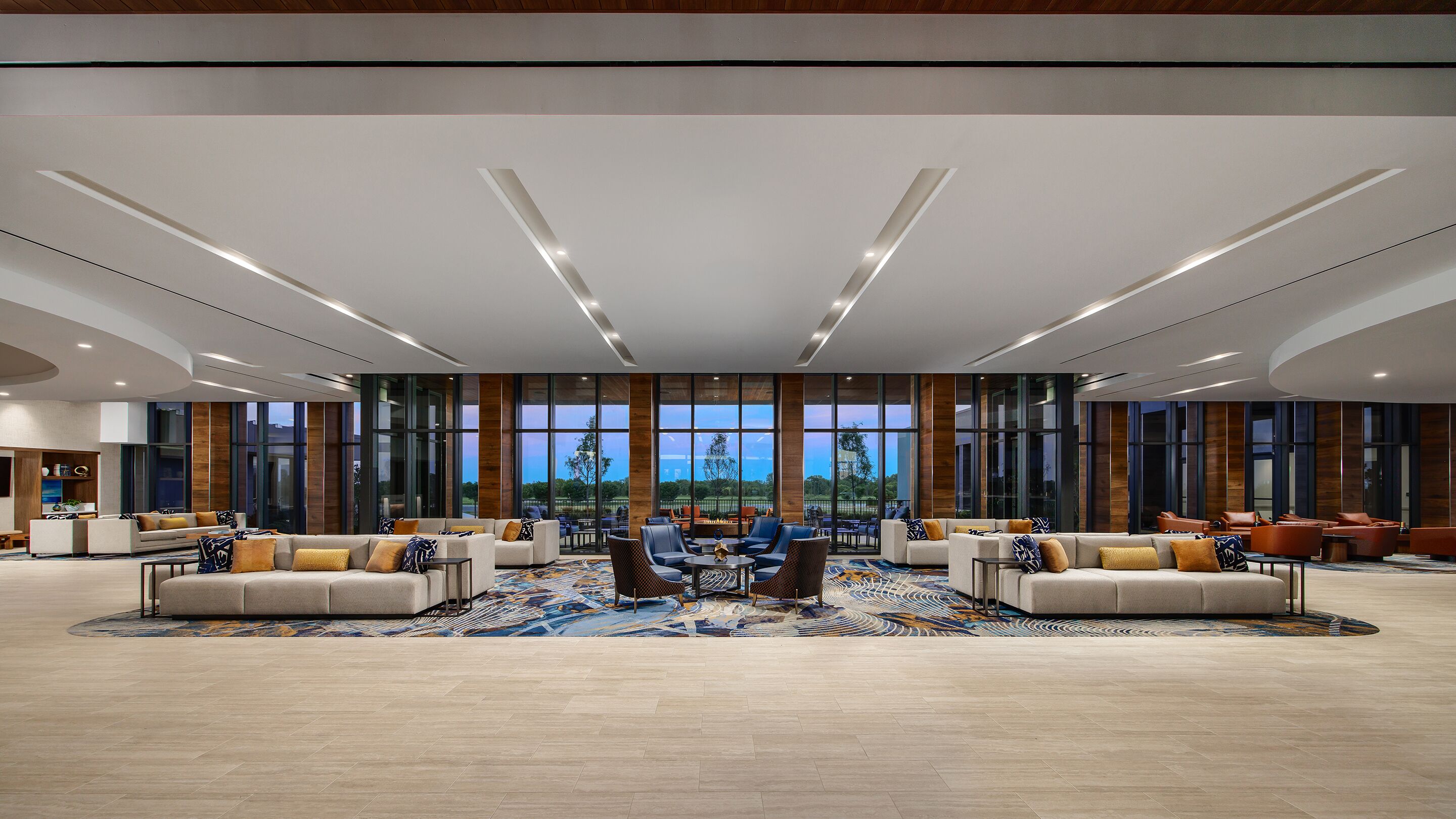 A spacious lobby with a central seating area, large windows, and a view of the outdoors.