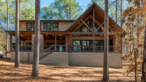Une cabane avec une façade en bois, de grandes fenêtres et une véranda couverte.