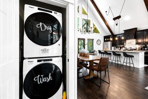 Een moderne keuken met donkerhouten kasten, een centraal eiland met barkrukken, en een eethoek met een houten tafel en stoelen.