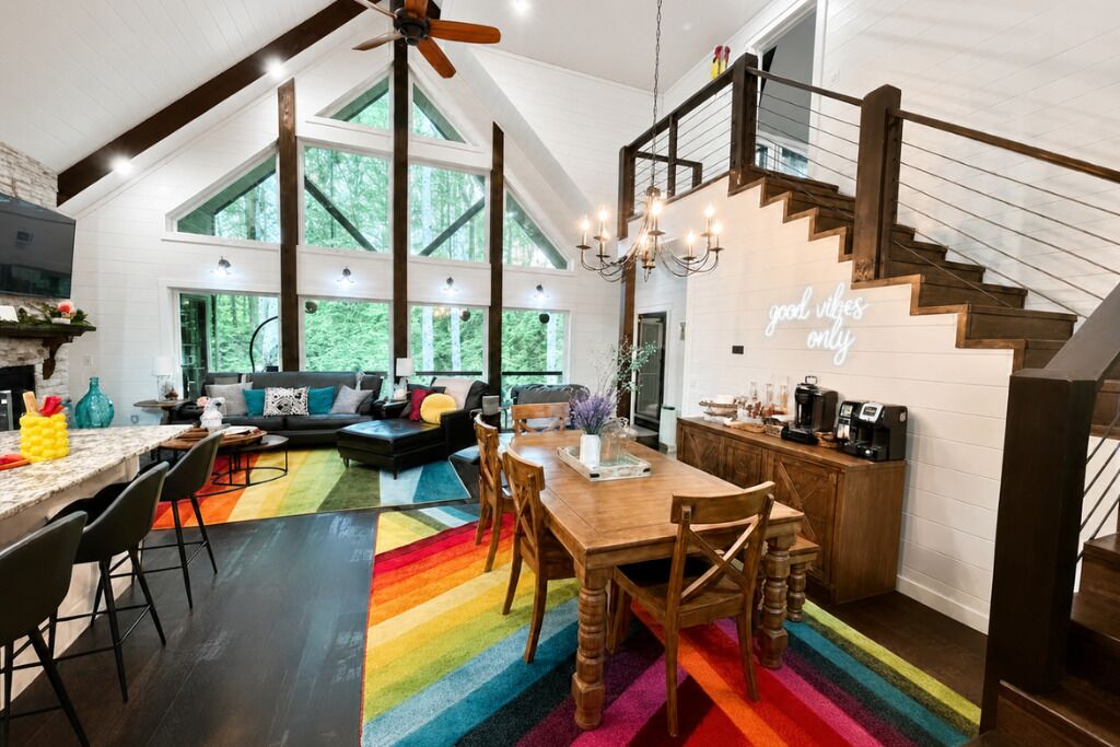 A spacious kitchen with a dining area, a staircase, and a large window overlooking greenery.