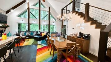 A spacious kitchen with a dining area, a staircase, and a large window overlooking greenery.