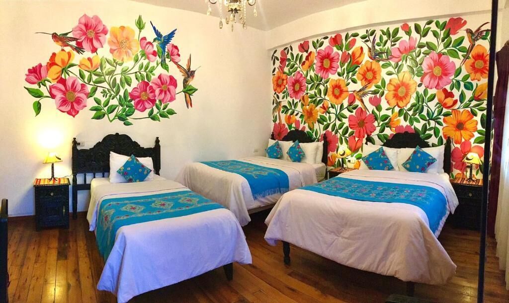 A room with two beds, a chandelier, and floral wall art.