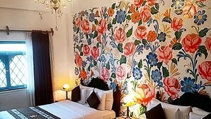A hotel room with two beds, a chandelier, a floral wallpaper, and a window with curtains. - Casona Dorada Hotel (Cusco)