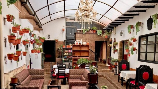A cozy, well-lit interior with a high ceiling, multiple seating areas, and numerous potted plants. - Casona Dorada Hotel (Cusco)