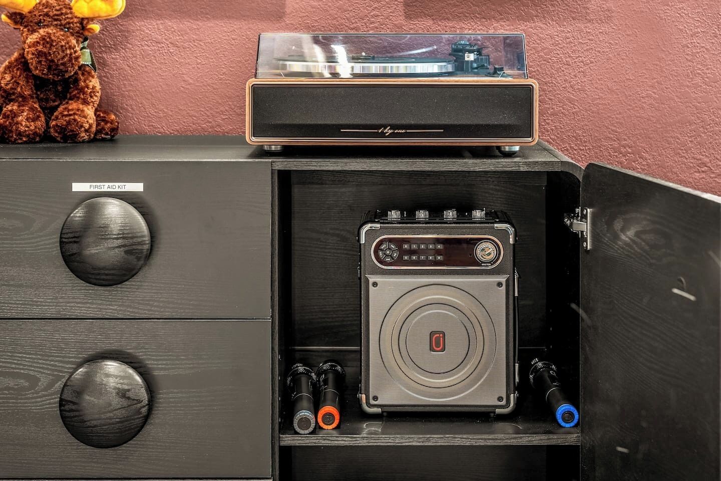 Ein Holzkabinett mit einem Erste-Hilfe-Set, einem Vintage-Radio und einem Teddybären.