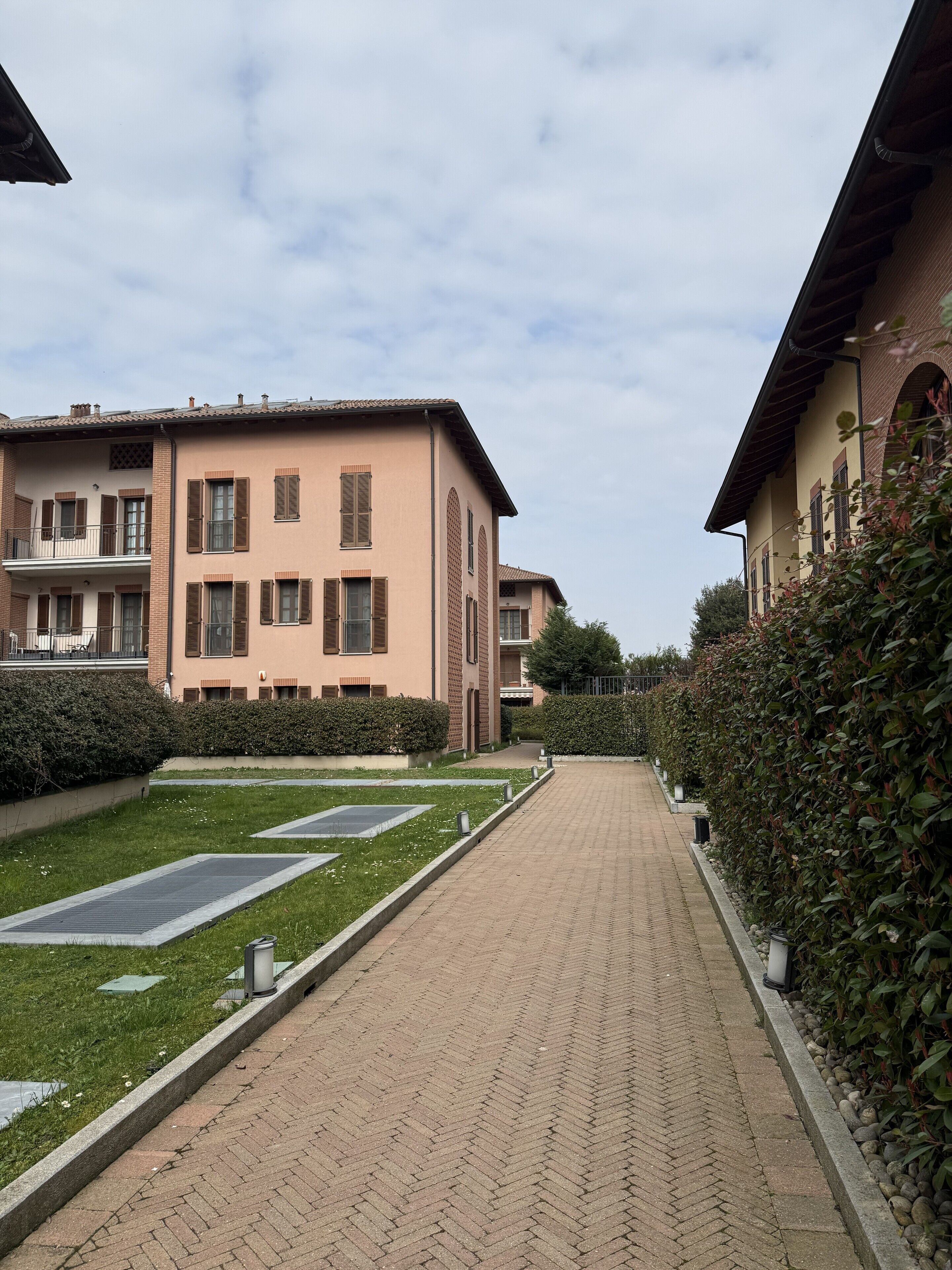 A pathway leading to a building with a brick facade and multiple windows.