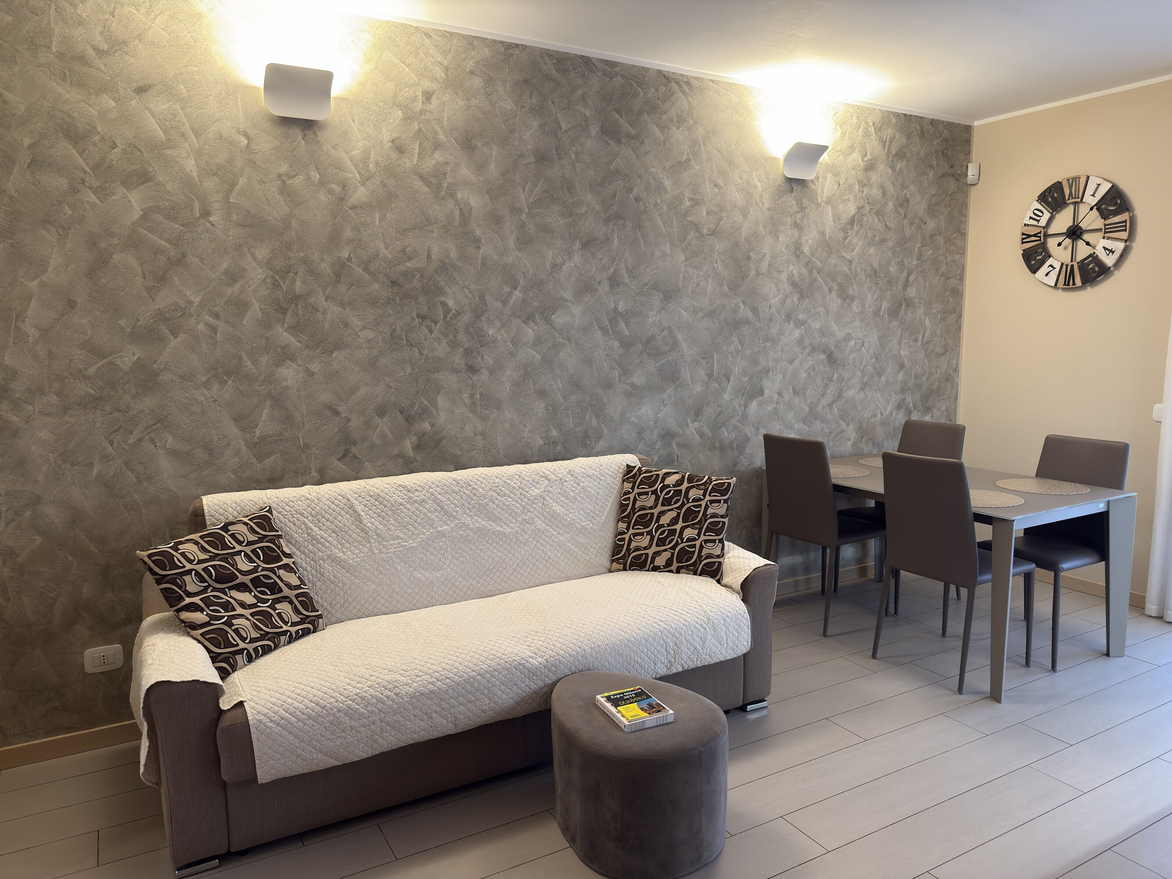 Un salon moderne avec un canapé, un pouf et une table à manger avec des chaises.