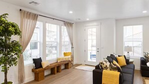 A modern living room with a wooden bench, a black sofa, and a potted plant. - Modern Southern Utah Home: 4BR, Dog-Friendly, EV Charger (Washington)