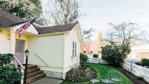 A small, single-story house with a front porch and a small garden area. - Cottage Nine in Jacksonville (Jacksonville)