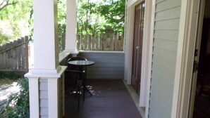 A covered porch with a table and chairs, a wooden fence, and a door leading inside. - Ida s Cottage in Jacksonville (Jacksonville)