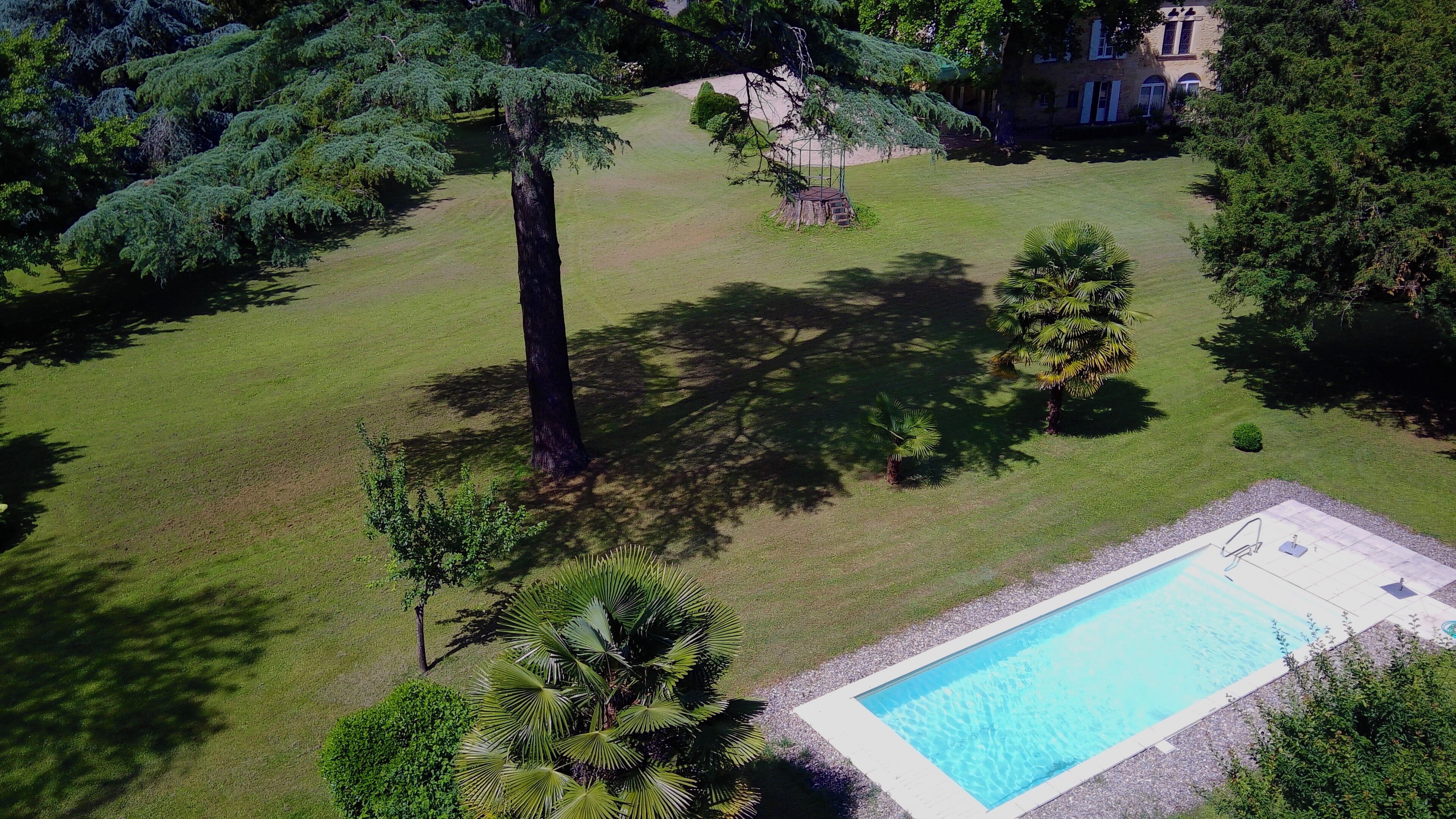 A swimming pool surrounded by a well-maintained lawn and trees.