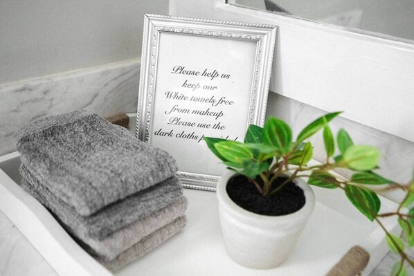 Un plateau blanc avec des serviettes pliées, un panneau encadré et une plante en pot.