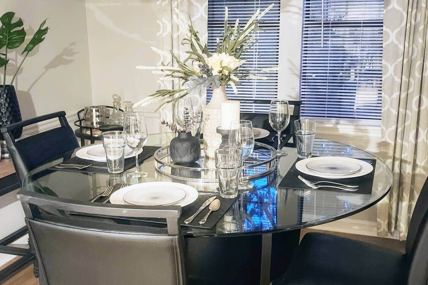 Une table à manger dressée avec des assiettes, des verres et un centre de table.