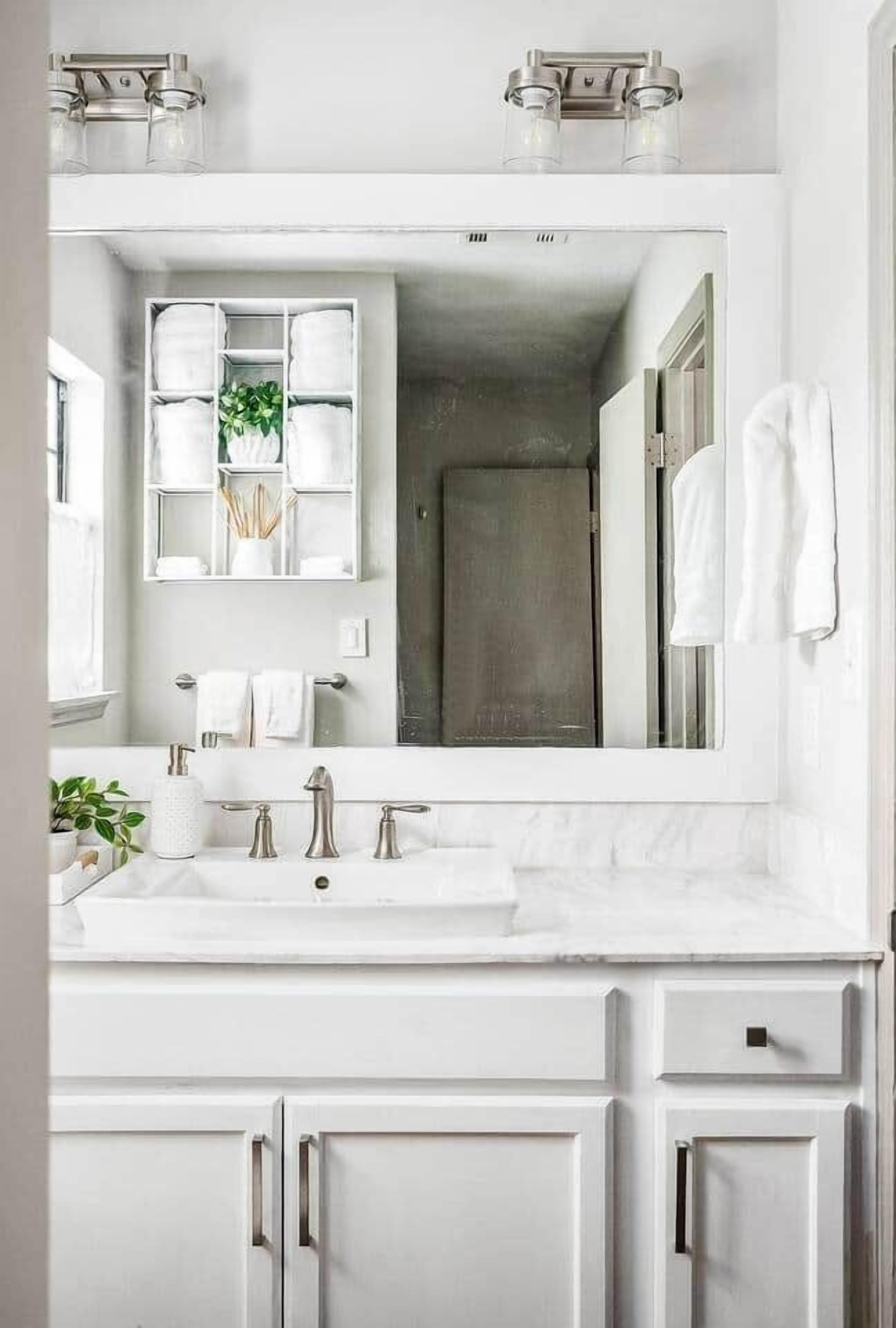 A bathroom with a large mirror, two sinks, and cabinets.