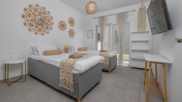 Une chambre moderne avec deux lits, une télévision et des œuvres d’art décoratives au mur.