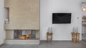 Un saló modern amb una llar de foc, un televisor penjat i dos vasetes decoratives sobre tamborets de fusta.