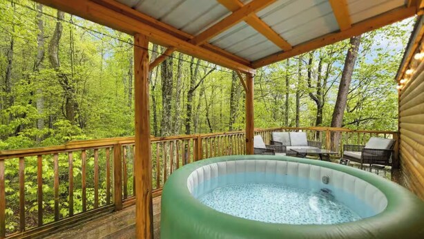 An outdoor hot tub on a wooden deck surrounded by a forest.