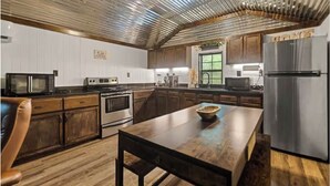 A modern kitchen with wooden cabinets, stainless steel appliances, and a wooden dining table.