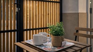 Een houten tafel met twee witte mokken en een gevlochten plantenpotje op een bloemenonderzetter.
