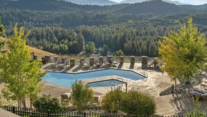 A pool area with lounge chairs and a view of a forested mountain range. - Serene Suncadia Escape! Mountain Views + Fireplace + Lodge Pool Access! (Cle Elum)