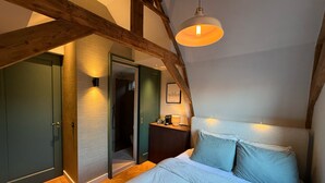 A bedroom with a bed, a nightstand, a desk, and a hanging light fixture. - Vermeer - luxury authentic room at Museumplein (Amsterdam)
