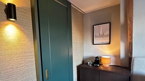 A hallway with a teal door, a wall-mounted light, a framed picture, and a small table with a lamp. - Vermeer - luxury authentic room at Museumplein (Amsterdam)