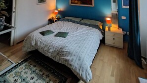 A bedroom with a bed, two bedside tables, a hanging lamp, a painting on the wall, and a window with curtains. - Cozy and bright apartment ideal for two people (Milano)