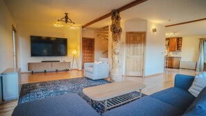 A modern living room with a flat-screen TV, a sofa, a coffee table, and a wooden accent wall. - Unbeatable 🏔️  Views, Serene, Fall Foliage, Hike, ATV Access (South Fork)