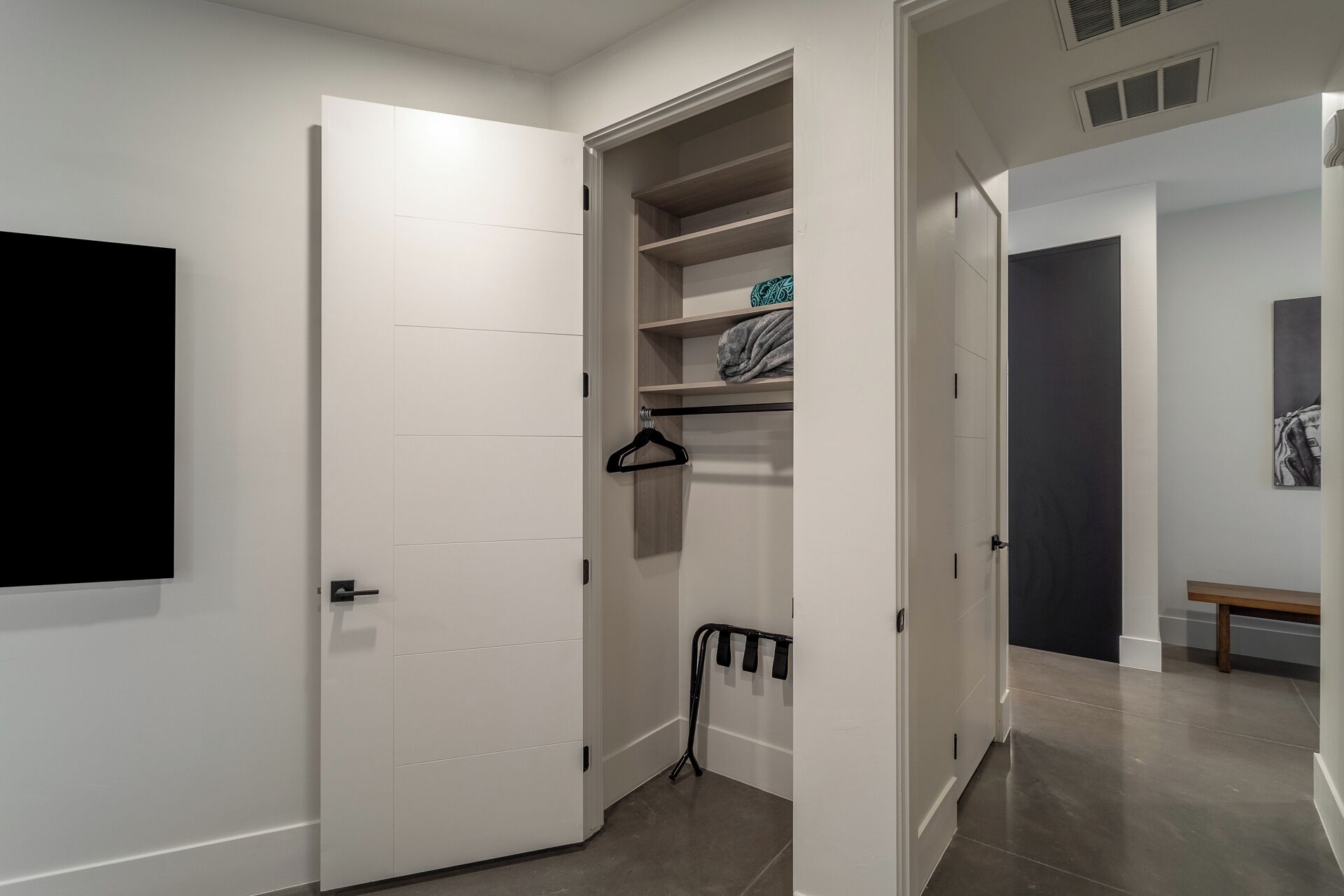 A hallway with a white door, a coat rack, and a bench.